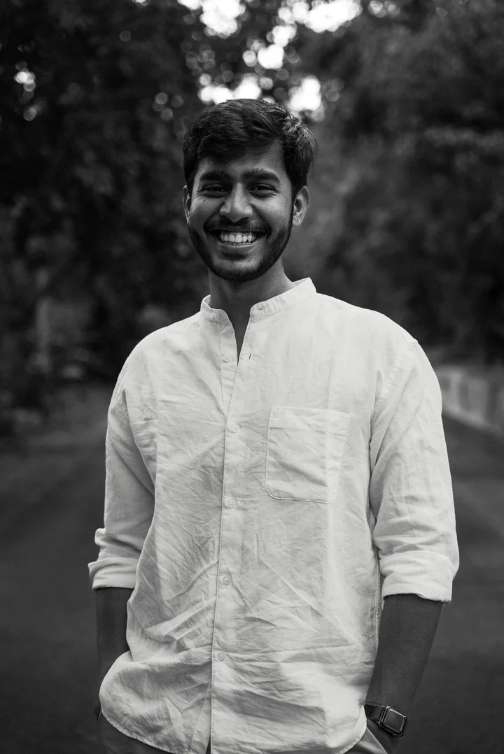 Abhi smiling outdoors in a white shirt